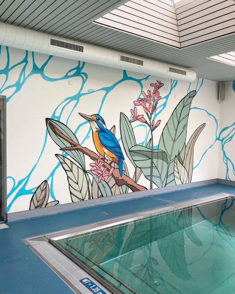 Wandgemälde eines Vogels und tropischer Pflanzen an einer Poolwand, reflektiert im Wasser.